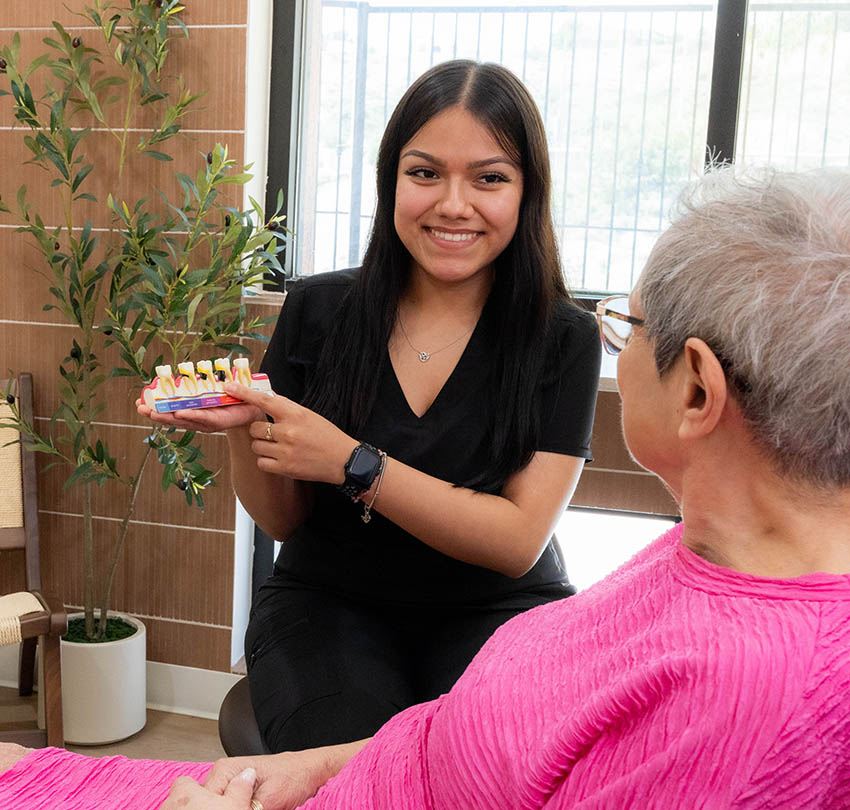 Dental team member explaining a tooth model to a seated patient